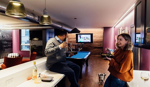 a man and a woman in a room with a pool table and tv